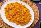 A plate of Nigerian Jollof rice served on a woven mat