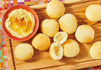 A wooden board with pita bread and a bowl of hummus