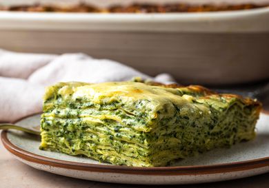 A slice of spinach lasagna, shot from the side so that all of the layers are visible.