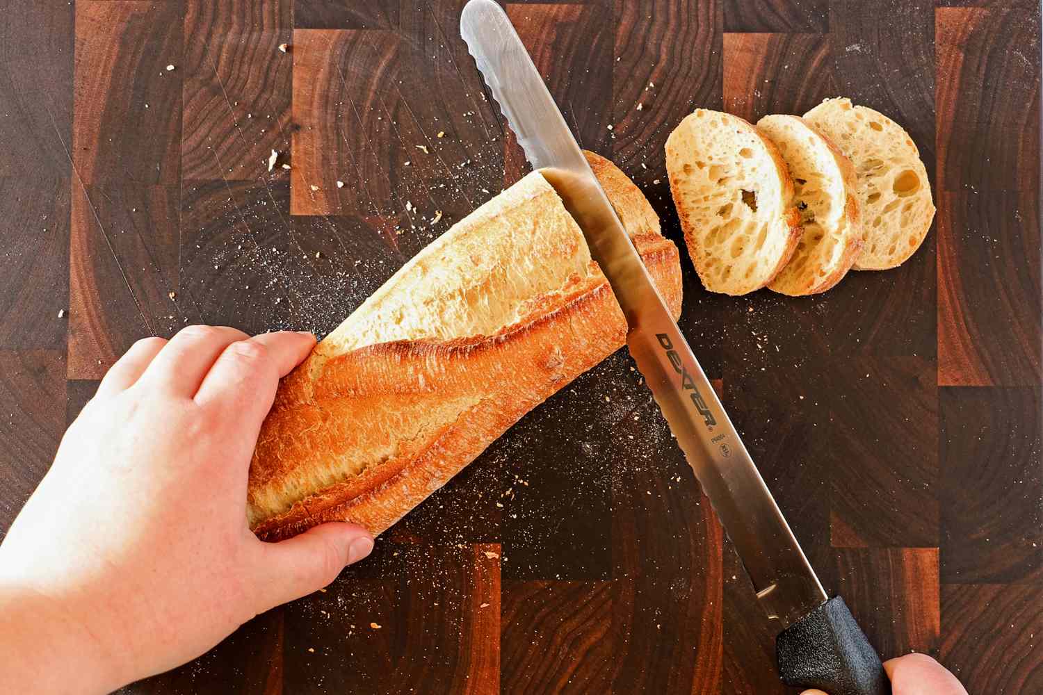Person slicing bread with Dexter-Russell Basics 10-Inch Bread Knife With Black Polypropylene Handle