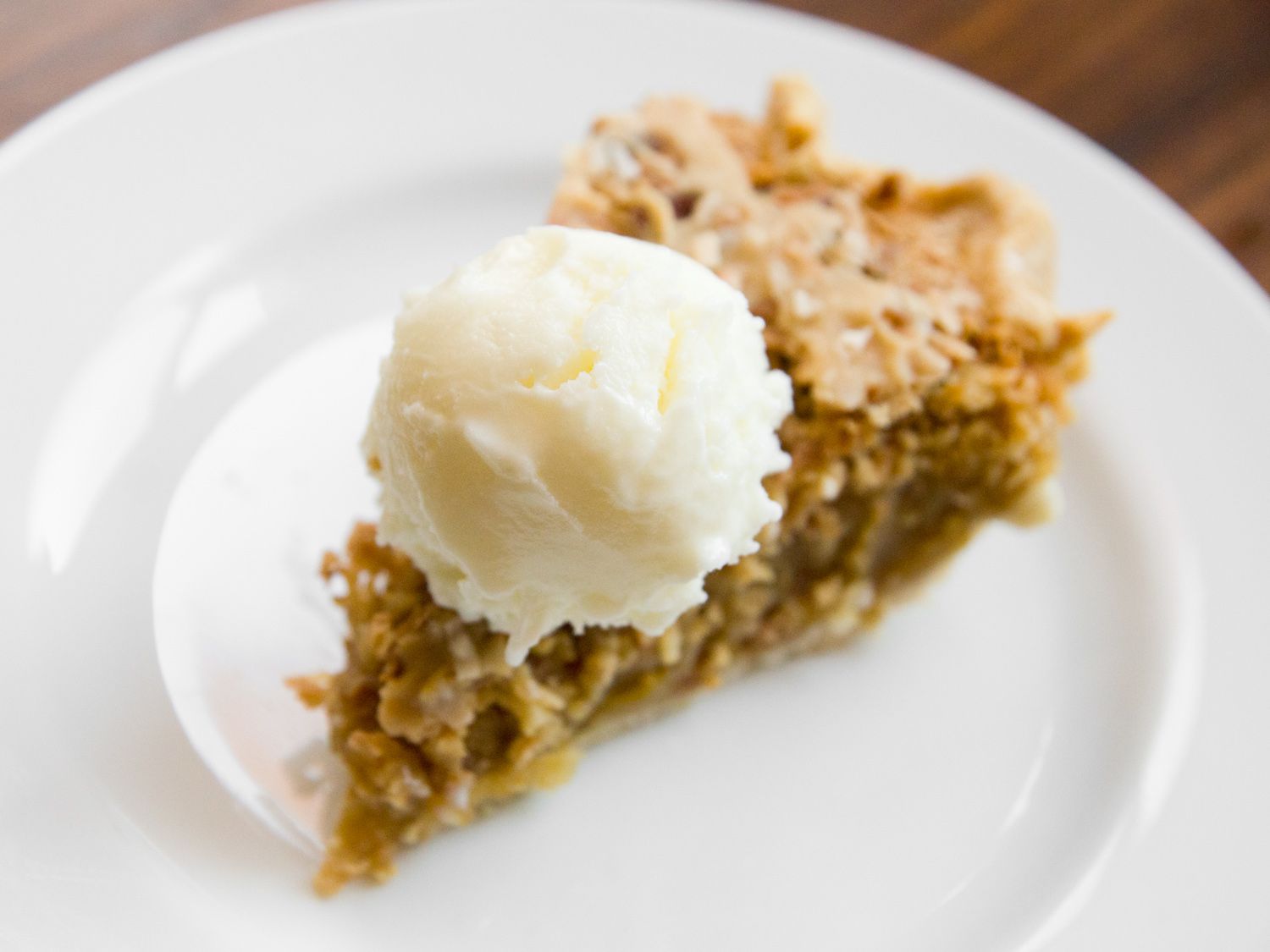 A scoop of ricotta gelato perched atop a slice of pie.
