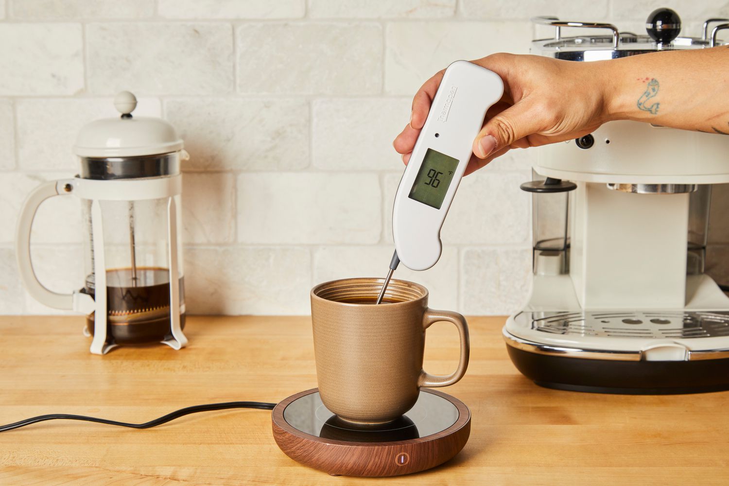 Person checking temperature of coffee with an instant-read thermometer in Sweetful Coffee Mug Warmer