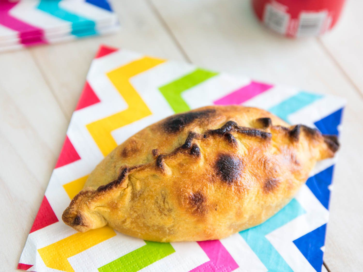 A finished salteña, served on a colorful zig-zag-patterned napkin.