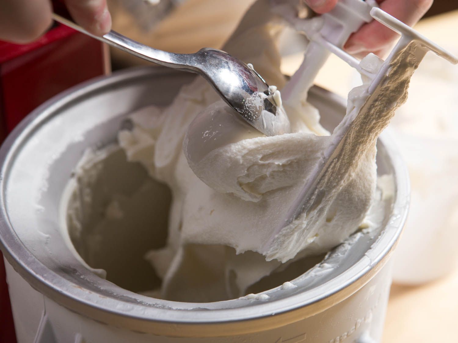 Scraping soft-churned ice cream from the paddle of an ice cream freezing core.