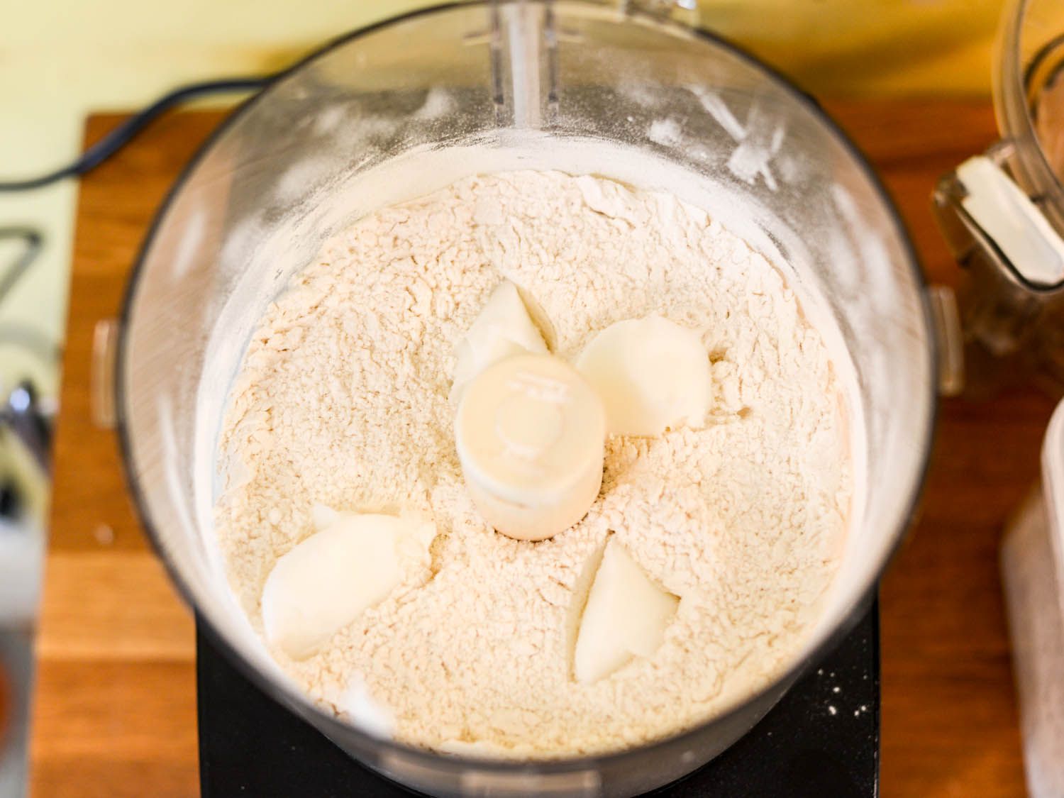 Chunks of lard and flour in food processor bowl.