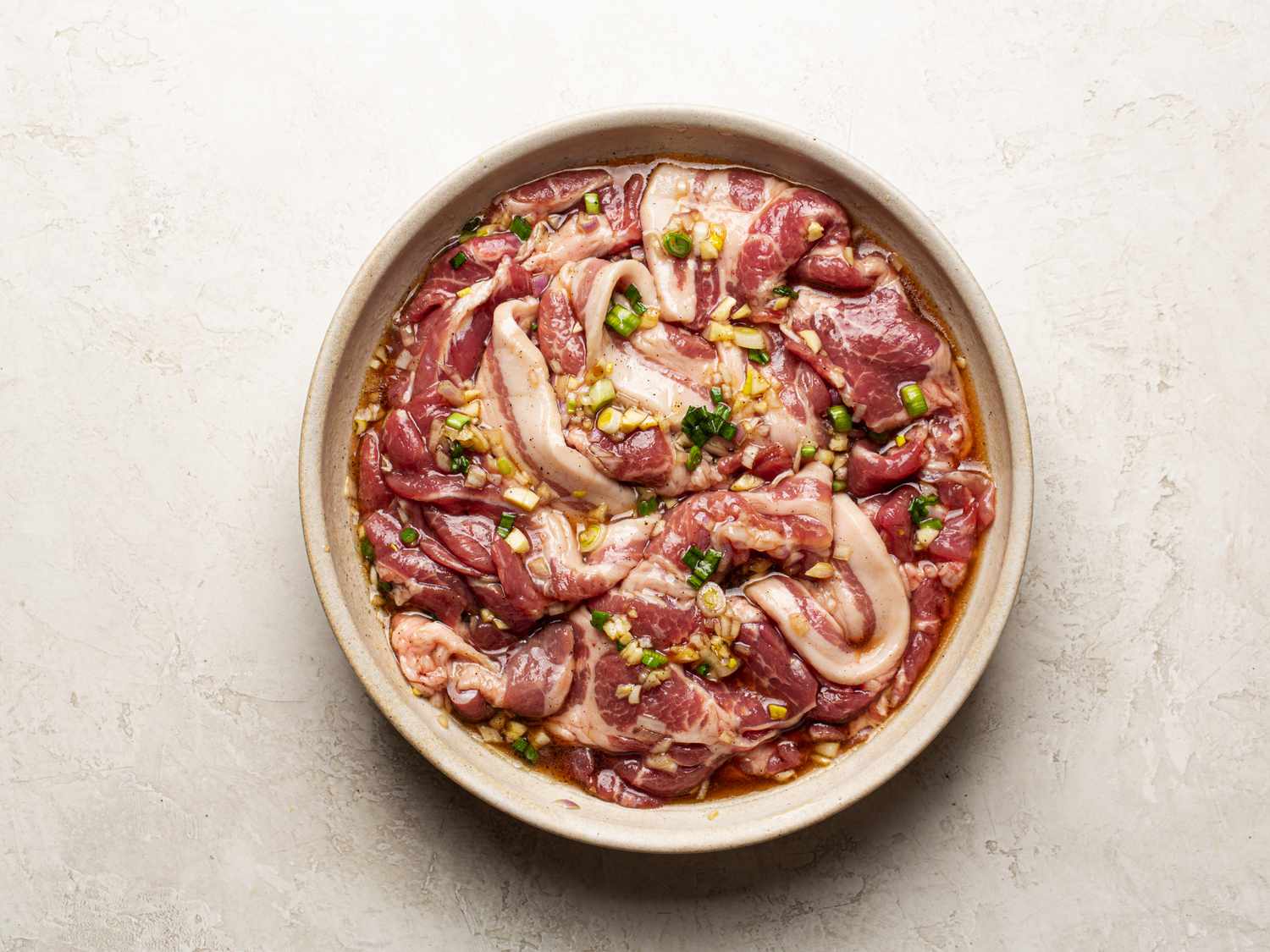 Overhead view of pork marinating in a bowl