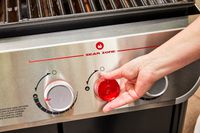 A person adjusts the temperature on the Weber Genesis E-335 Gas Grill