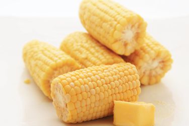 Small cobs of sous vide-cooked corn with a chunk of butter on the side.