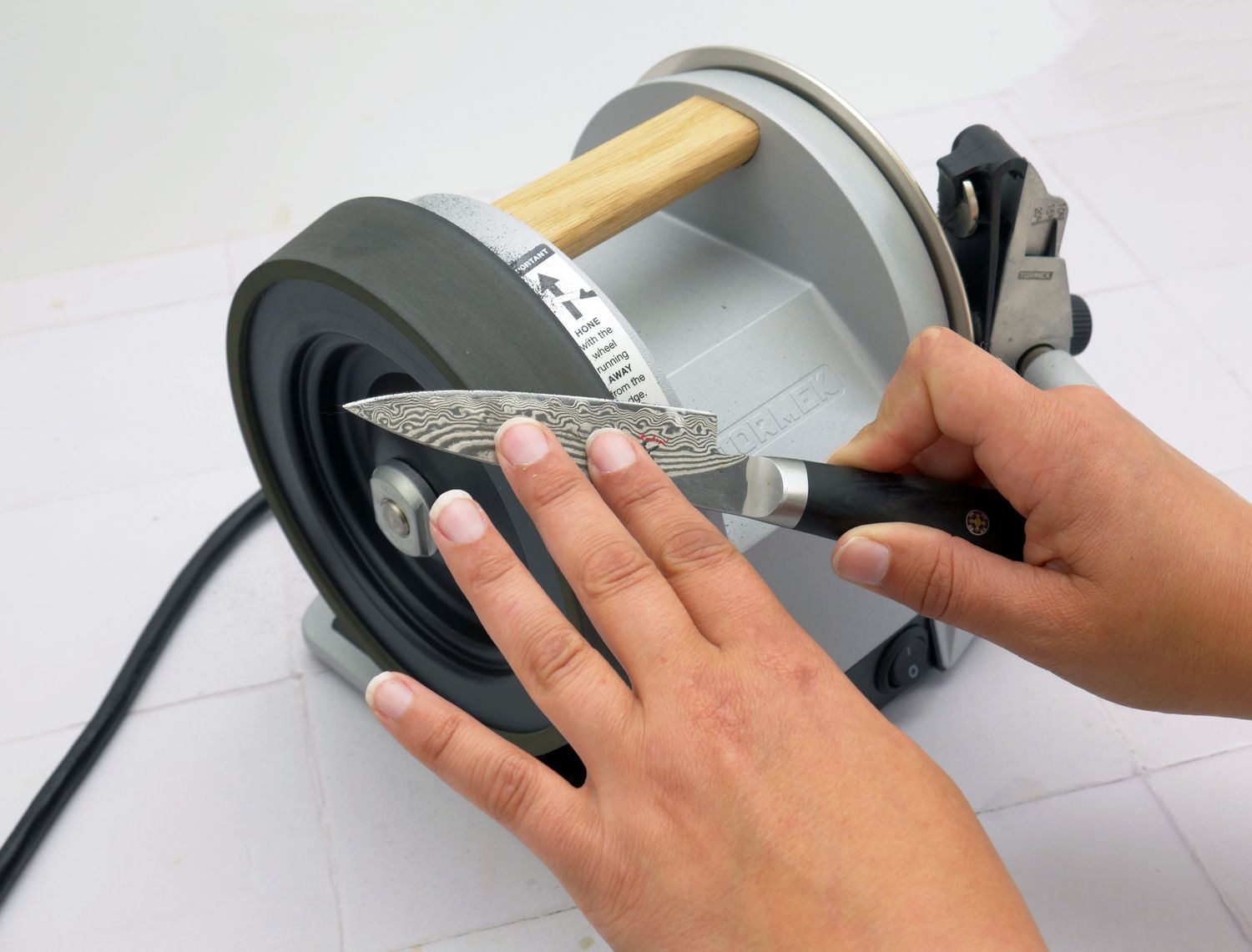 a person using the honing wheel to hone a paring knife