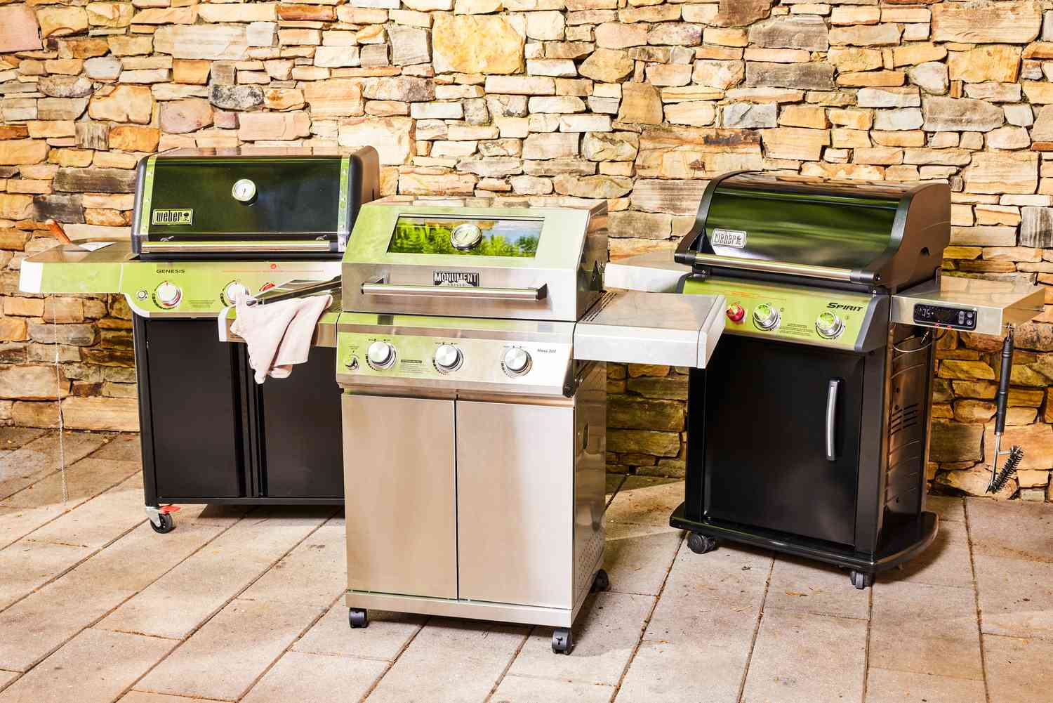 Three gas grills on a patio.