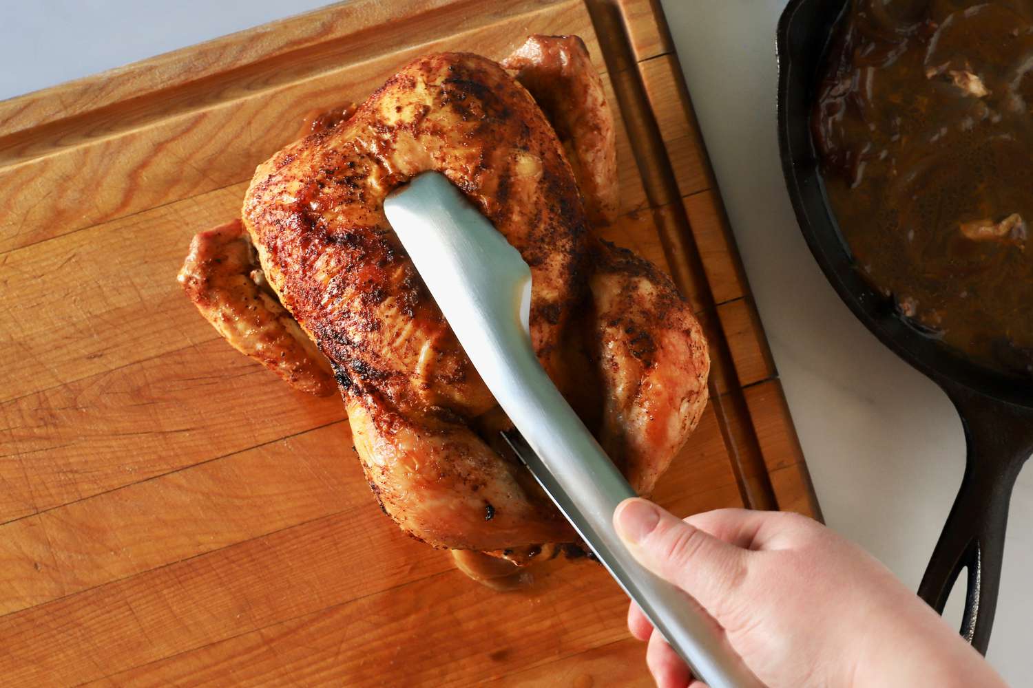 Hand using the Material Kitchen The Only Tongs to pick up a whole chicken