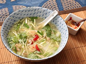 A bowl of easy chicken and ginger soup with rice cakes, chives, and quick-pickled garlic.