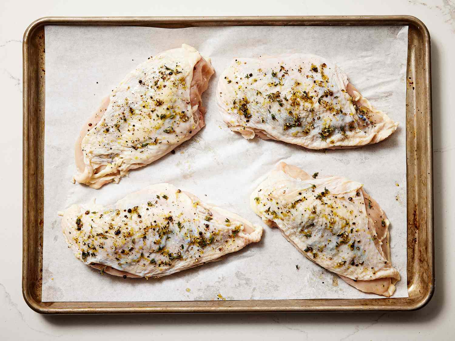 4 chicken breasts on a parchment paper lined sheetpan 