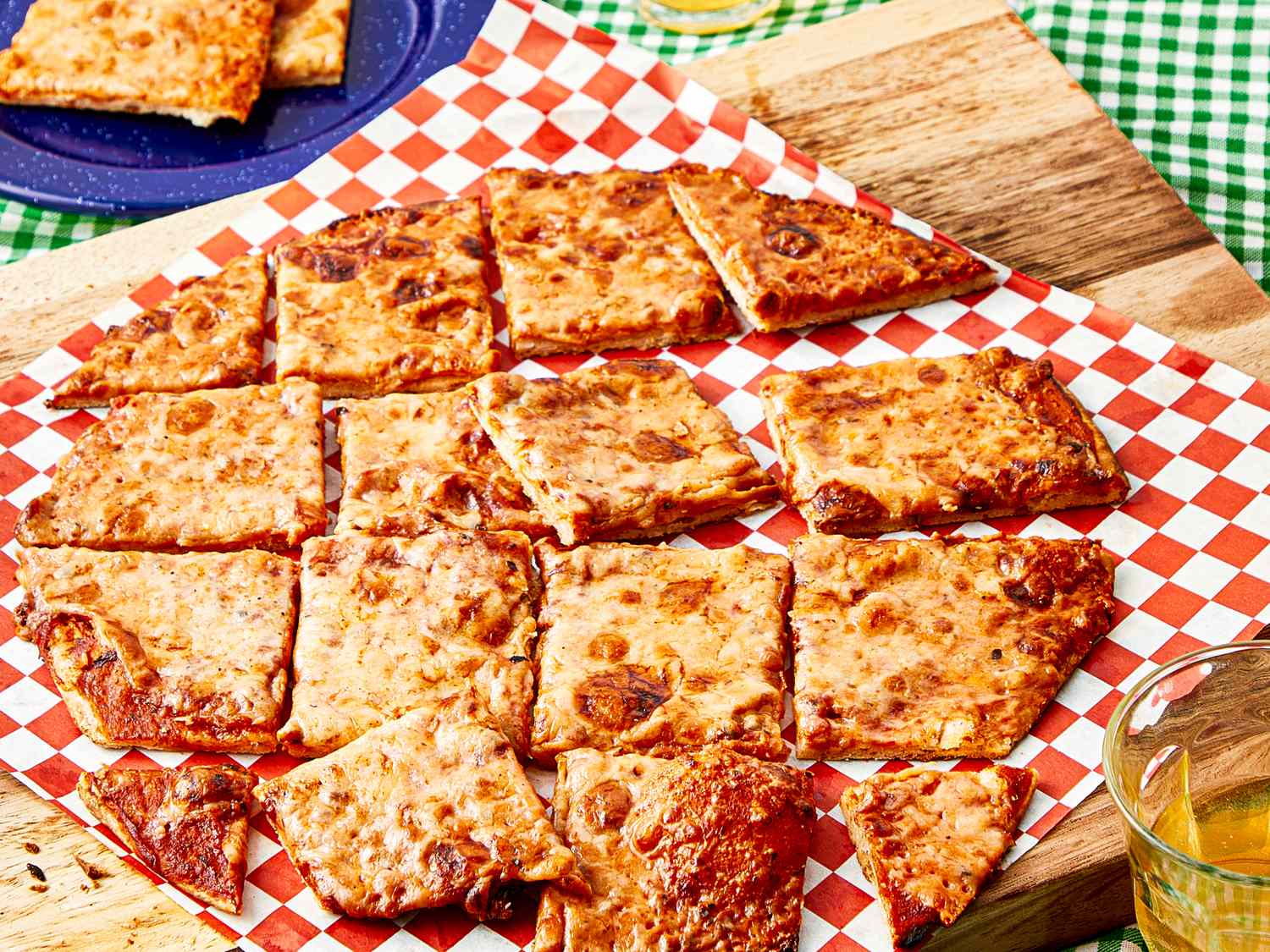 A St Louisstyle pizza sliced into squares on a checkered paperlined wooden board