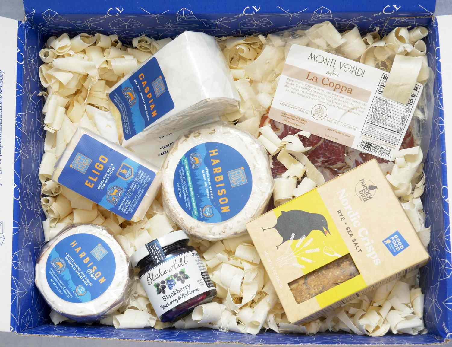 a box with four cheeses and crackers, jam, and dried meat
