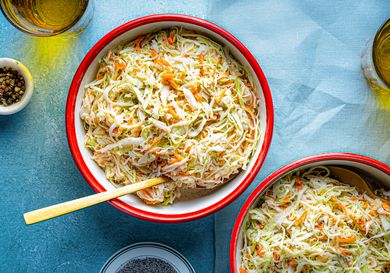 Two bowls of coleslaw with a wooden spoon on one