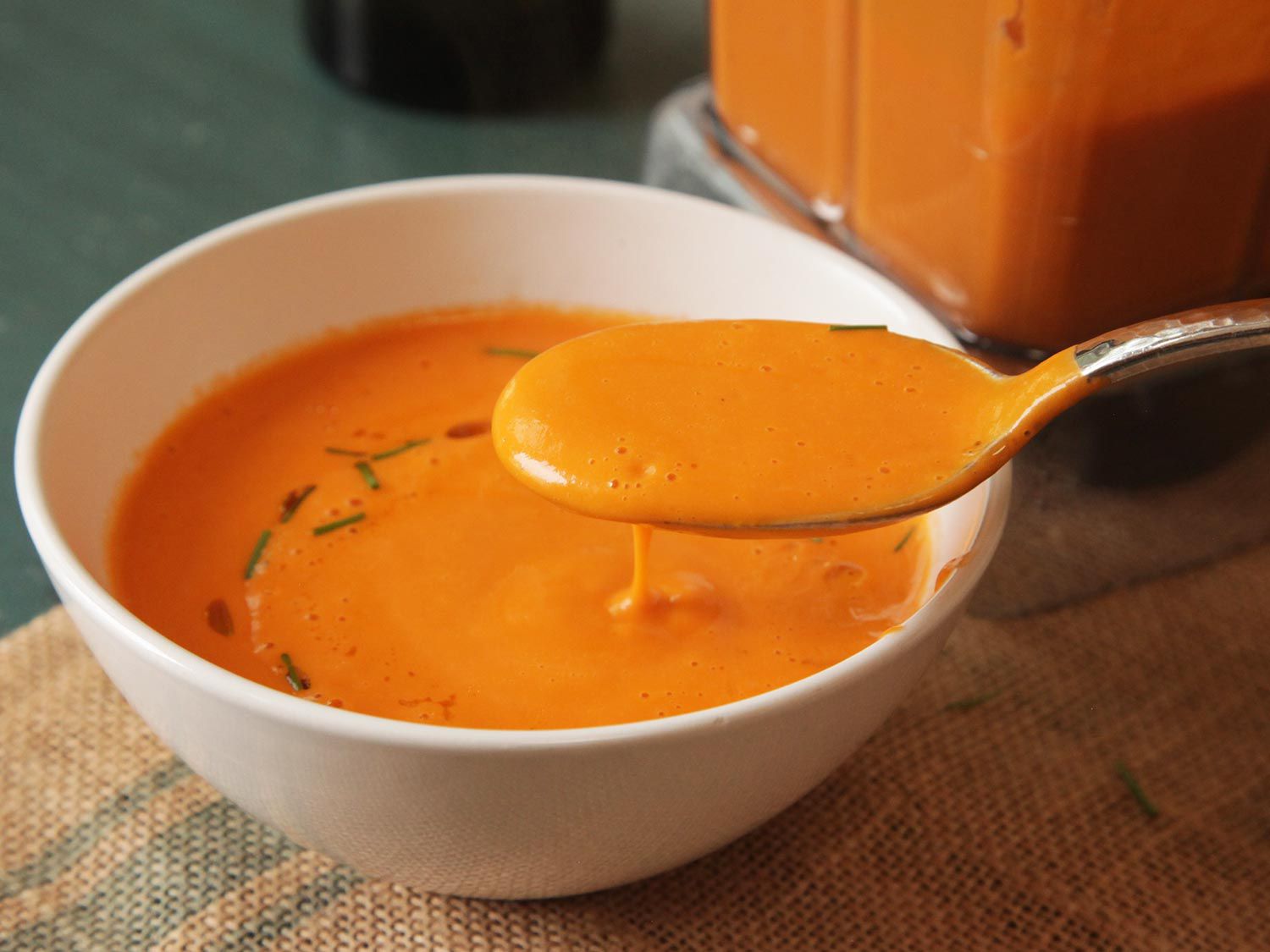 Lifting a spoonful of tomato soup from a bowl