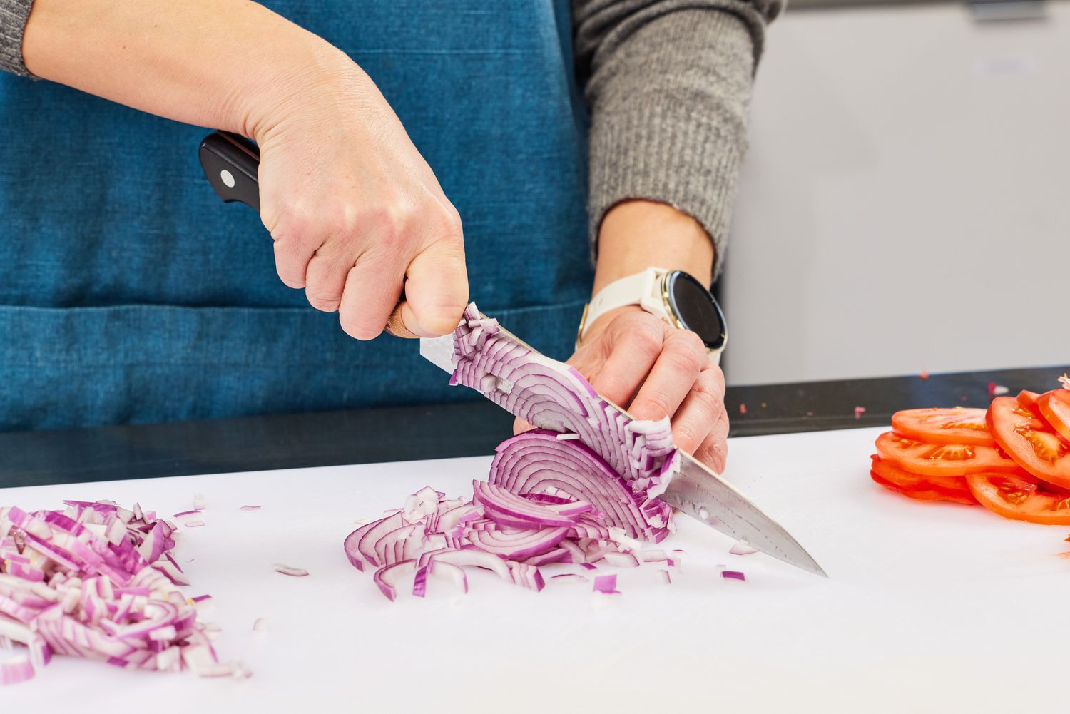 Hands slicing a red onion with a Misono UX10 8.2-Inch Gyutou