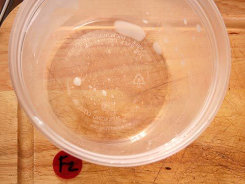 An almost empty pint container, showing very little whey in the bottom.