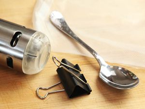 Closeup of the bottom of an immersion circulator, a spoon, and a binder clip.