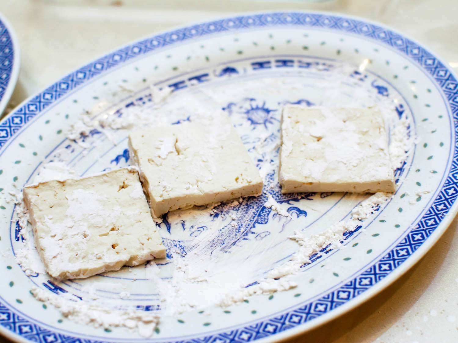 3 slices of tofu coated in seasoned cornstarch on a plate