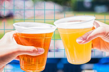 Two hands holding plastic cups of beer in a sports game setting