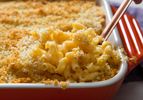 A rectangular casserole dish of macaroni and cheese with breadcrumbs on top. 