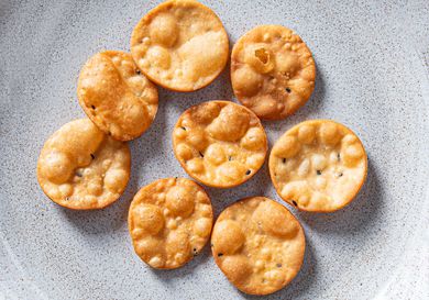 Golden brown chaat crisps resting on a ceramic plate.