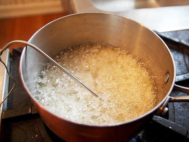 Thermometer resting in copper pot of boiling sugar