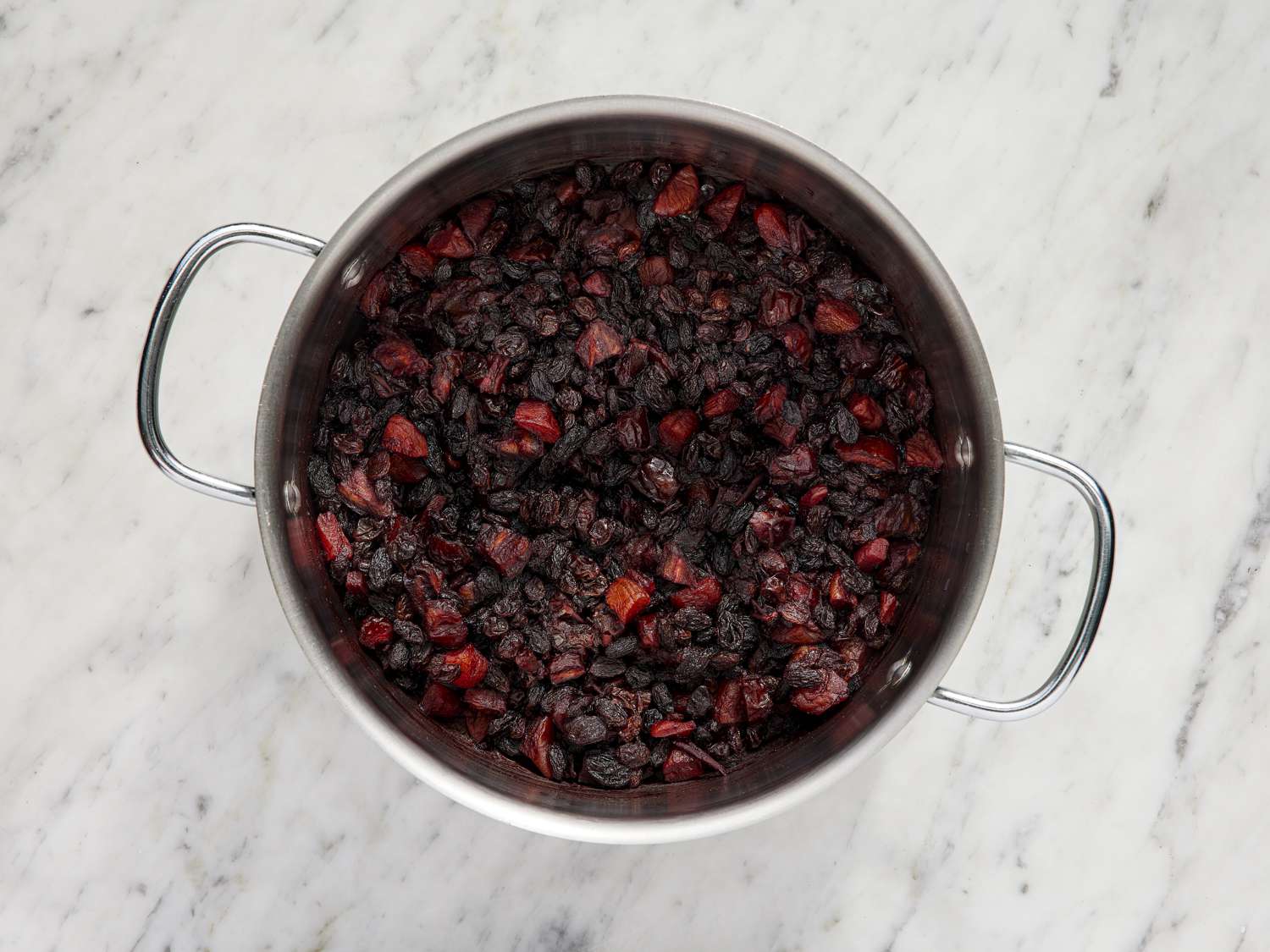 Overhead view of wine and fruit simmering in a pot