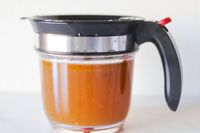 A measuring cup with a dark handle and a liquid inside