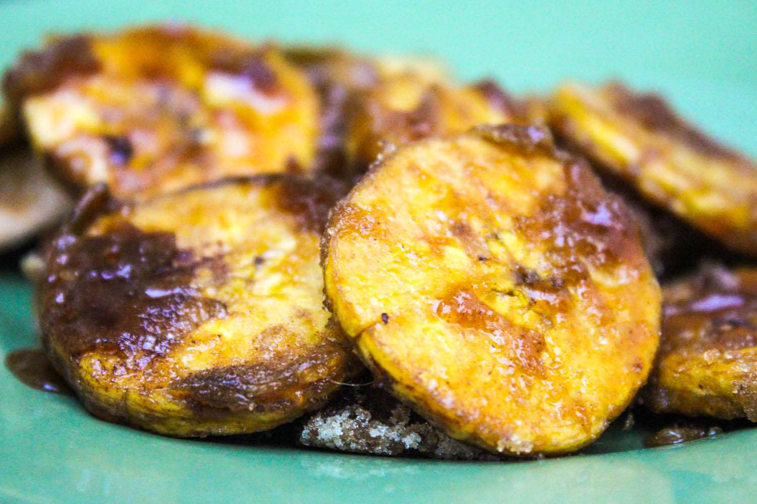 A close-up of plátanos calados on a green dish.