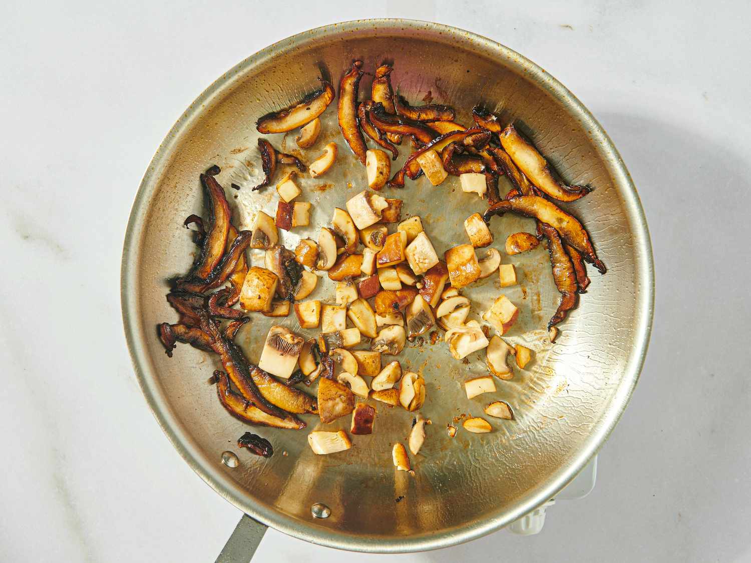 A skillet with cooked chopped mushrooms and tofu