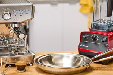 Coffee machine, blender, and steel frying pan on a wooden counter
