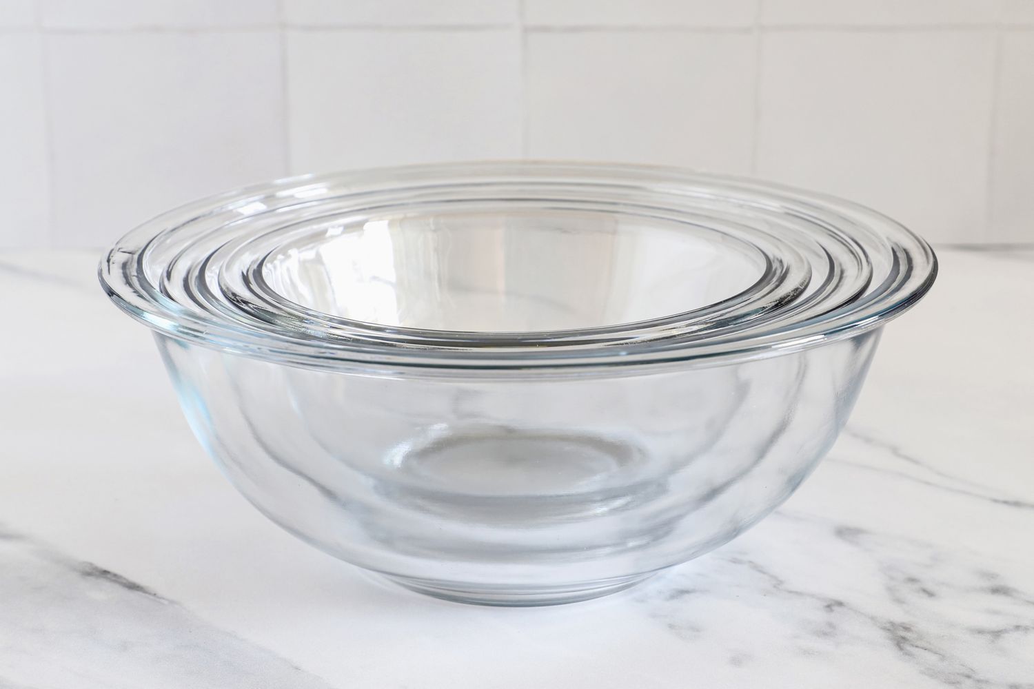A set of Pyrex nesting glass mixing bowls placed on a marble countertop