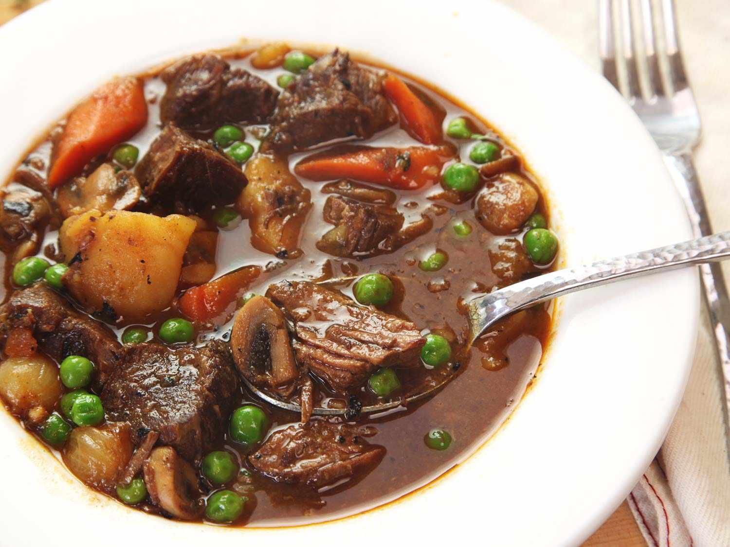 Close up view of a serving bowl of beef stew with vegetables. 