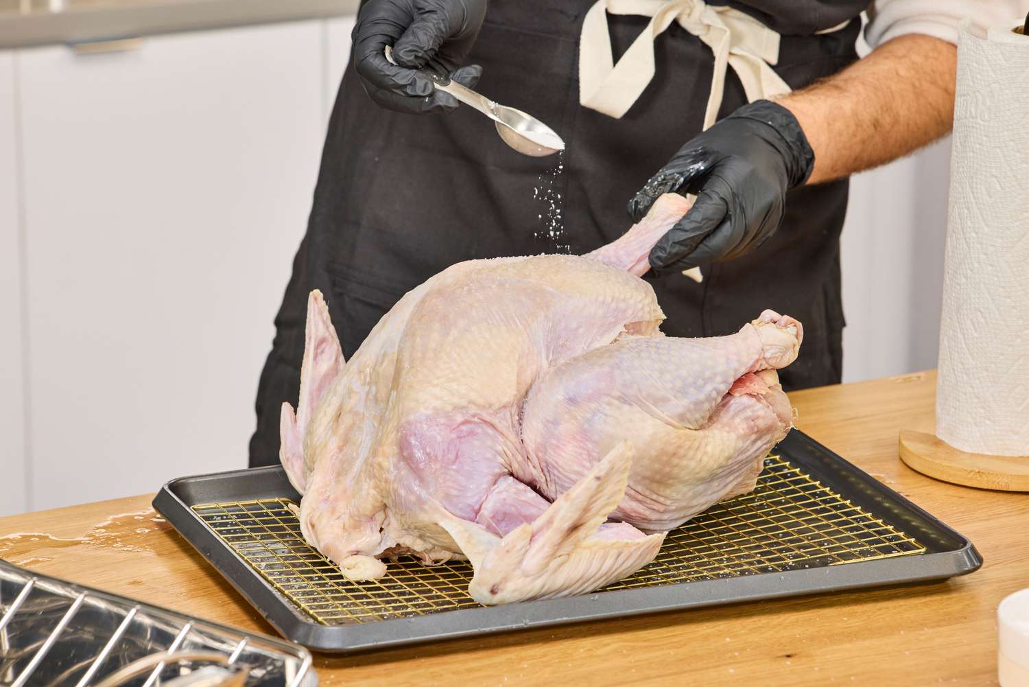 A person seasoning a raw Williams Sonoma Willie Bird Turkey