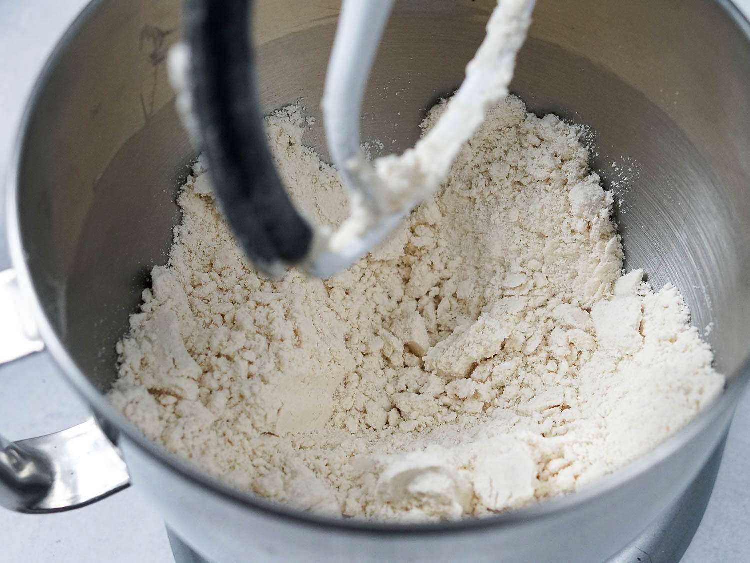 The flour and lard are mixed until crumbly in a stand mixer.