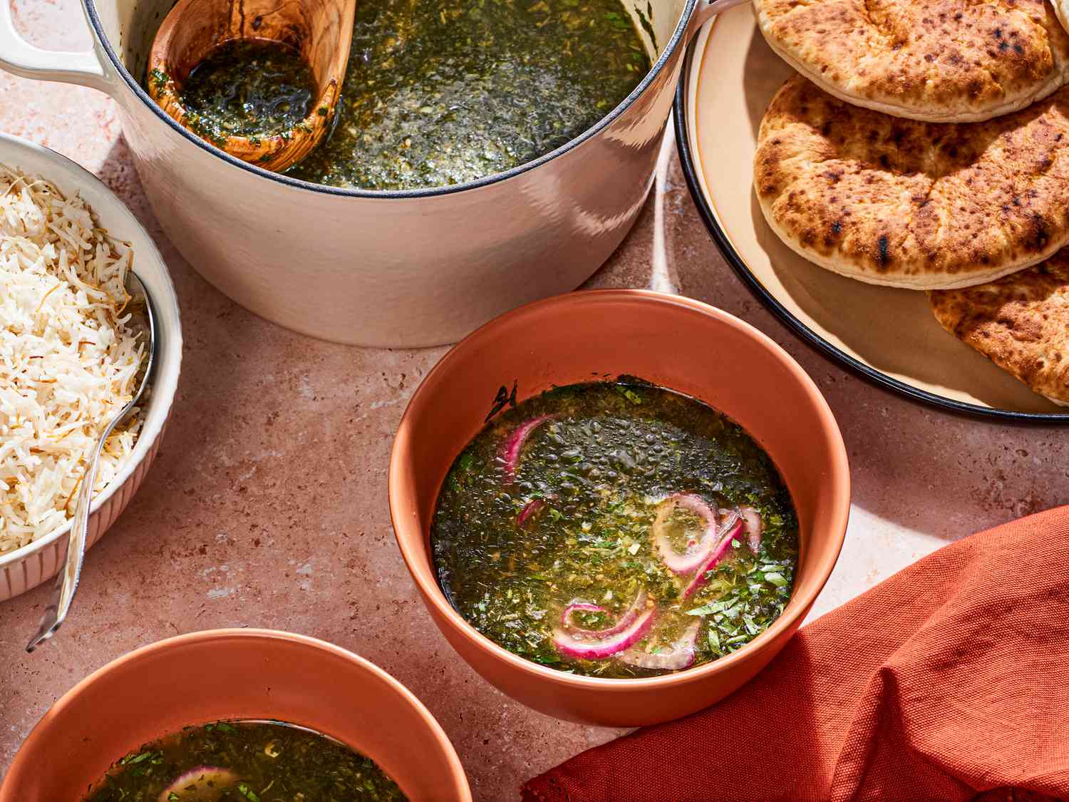 Molokhia soup in a bowl with bread on the side.