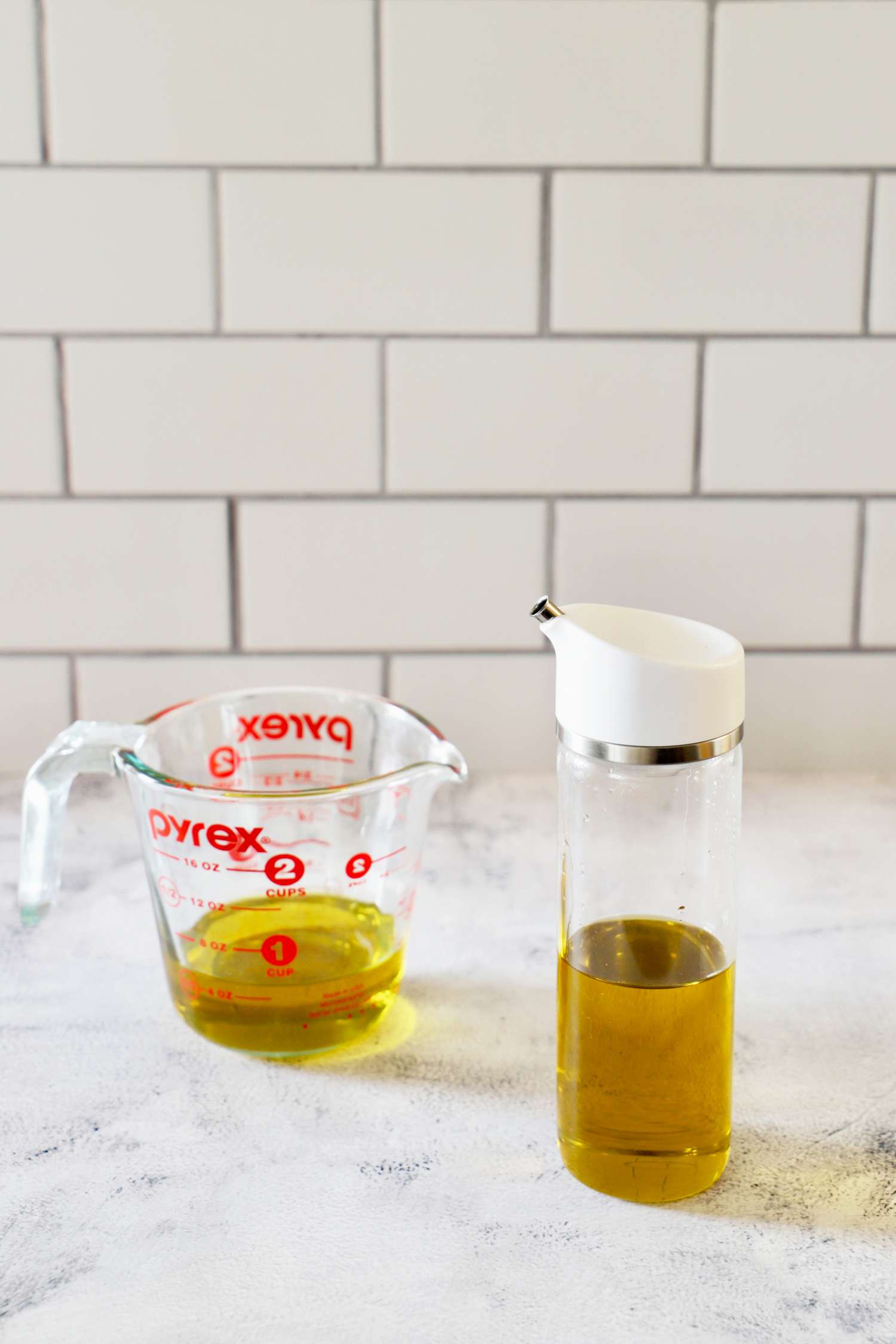 The OXO Precision Pour Glass Dispenser next to a cup of oil
