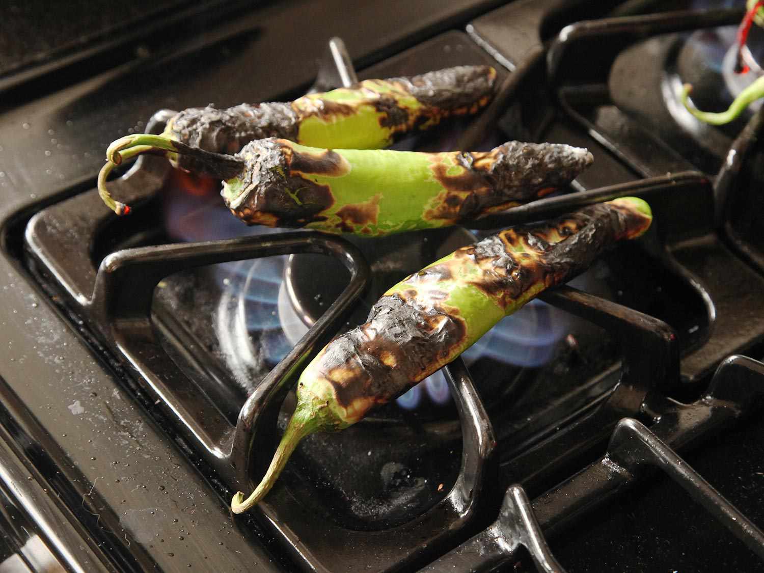 Charring chiles over a gas flame.