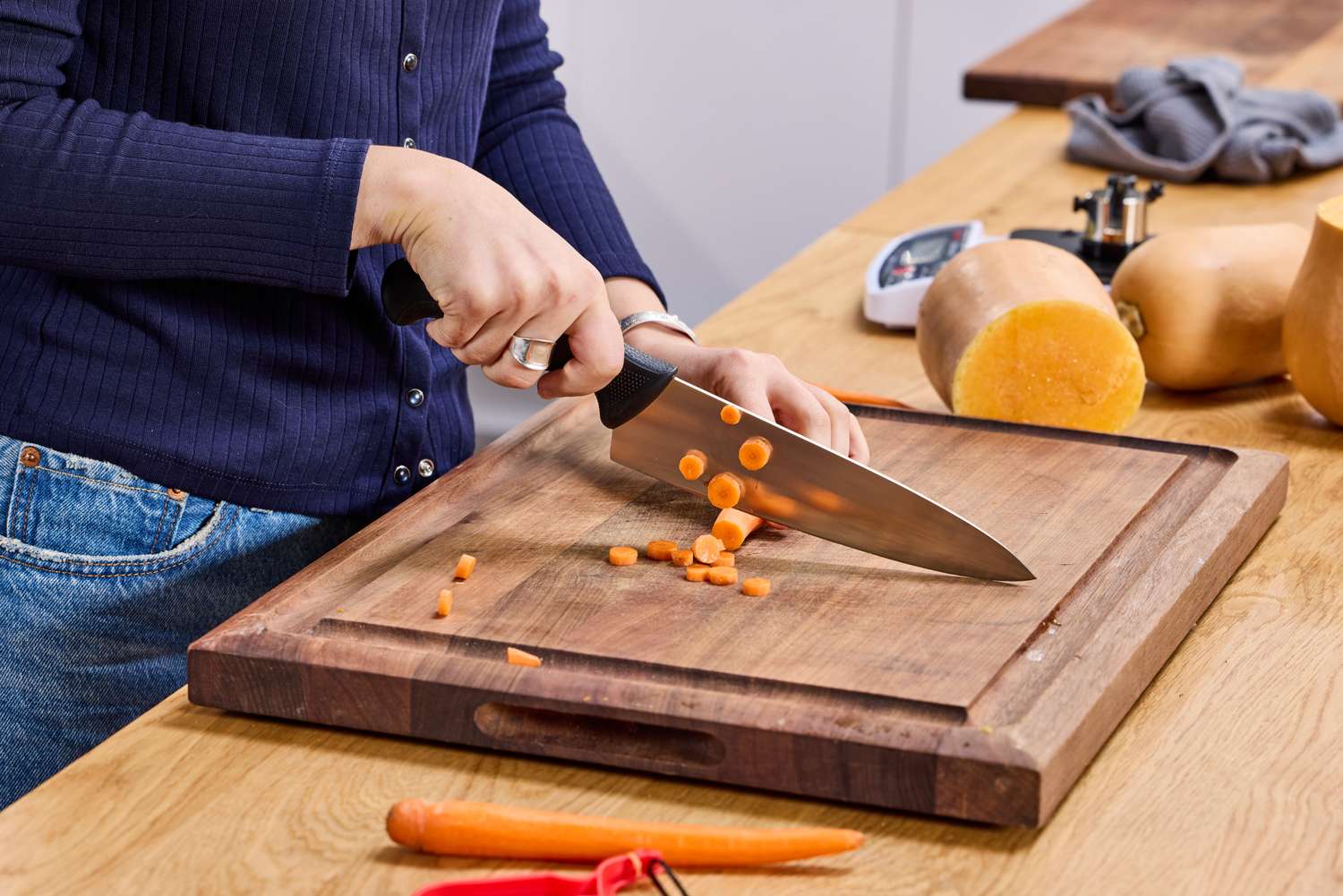 A person cuts a carrot using the Mercer Culinary 8-Inch Millennia Chef's Knife