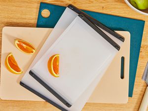 Three plastic cutting boards on a wooden countertop.