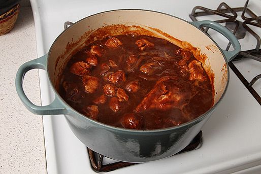 An enamel cast iron Dutch oven with ingredients for carne adovada. 