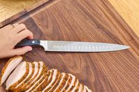 The Wüsthof Classic 9 Inch Hollow Edge Carving Knife on a cutting board