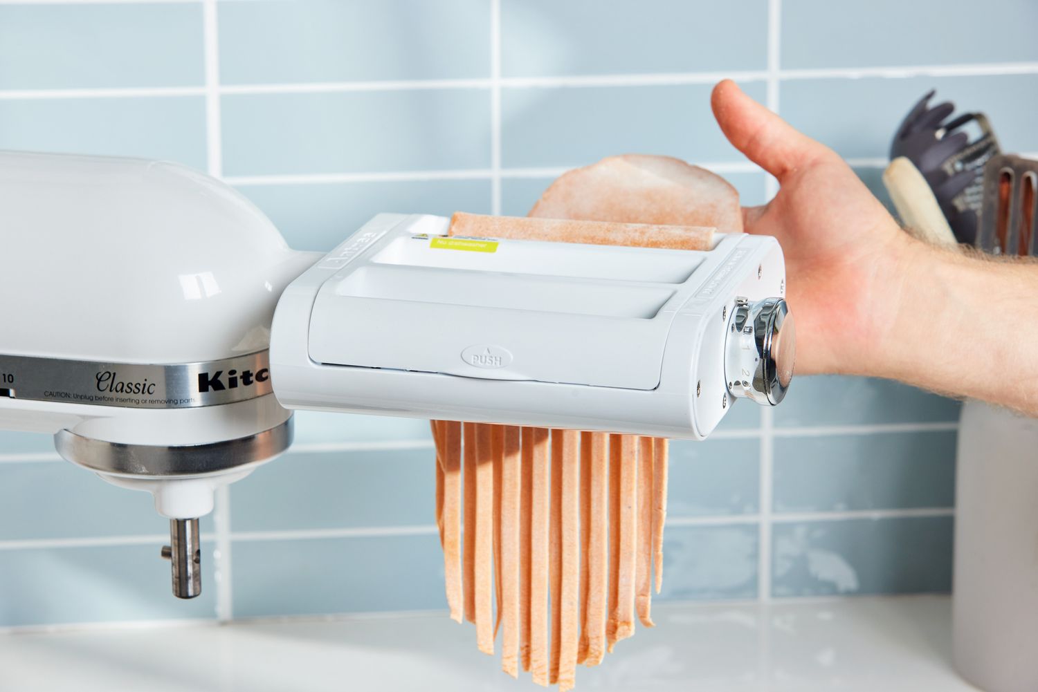 A person makes pasta using the Antree Pasta Maker Attachment 3 in 1 Set for KitchenAid Stand Mixers