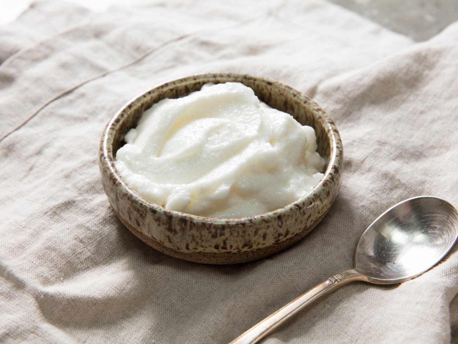 A small bowl of toum, Lebanese garlic sauce, with a spoon next to it.