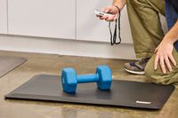 A weight is placed on the Sky Solutions Sky Mat 0.75-Inch Comfort Anti-Fatigue Mat