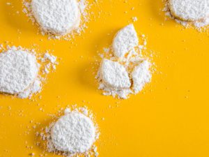 Powdered sugar-covered lemon meltaway cookies against a yellow background