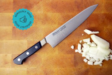 the misono chef knife on a cutting board with diced onion